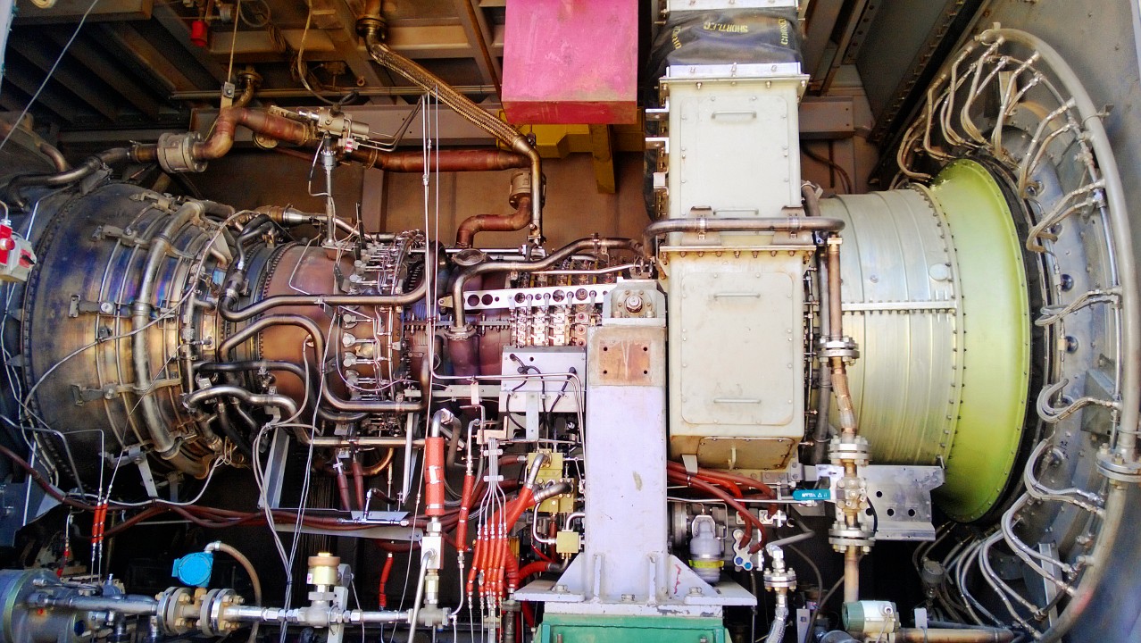 LM6000 gas turbine with its external casing, pipework and hoses in an industrial installation